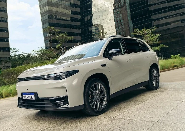 SUV elétrico Leapmotor C10 branco com placa visível estacionado em frente a edifícios corporativos espelhados modernos