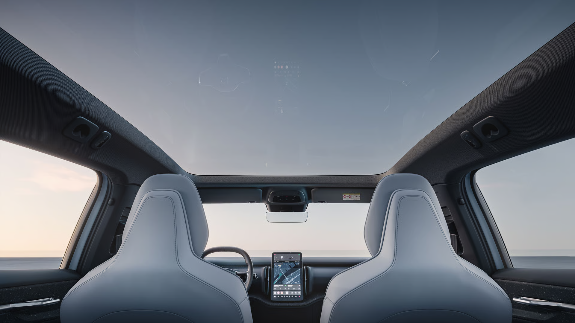 Vista interna da cabine do Volvo EX30 destacando o teto solar panor&acirc;mico de vidro